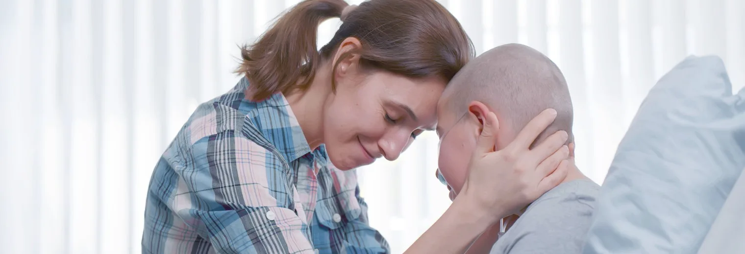 An image of a caring woman tenderly holding a cancer patient's head